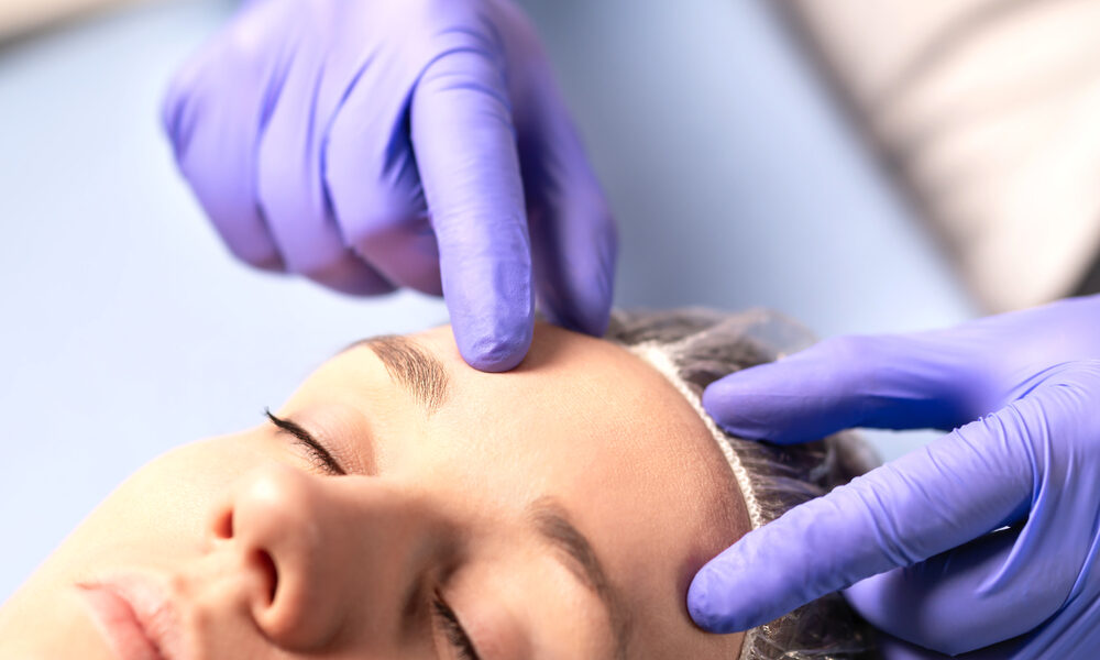 Dermatologista com a mão na testa de paciente