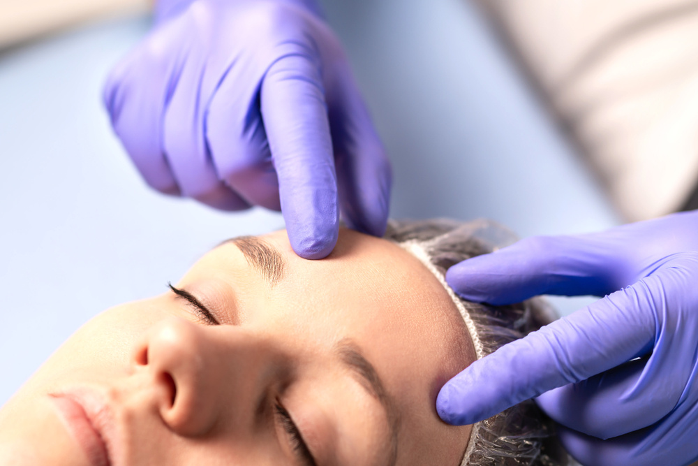 Dermatologista com a mão na testa de paciente
