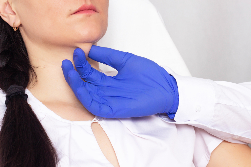 Médica com a mão na papada da paciente